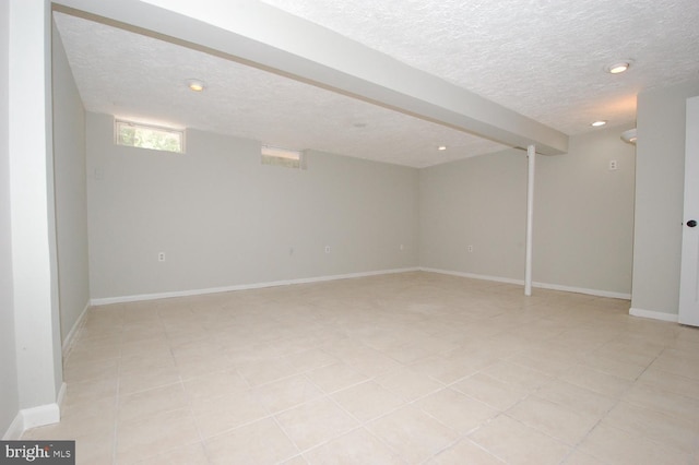 below grade area with light tile patterned floors, baseboards, recessed lighting, and a textured ceiling