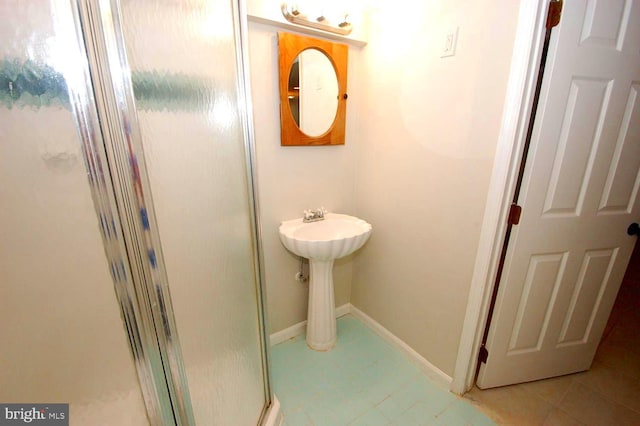 bathroom with baseboards and a stall shower
