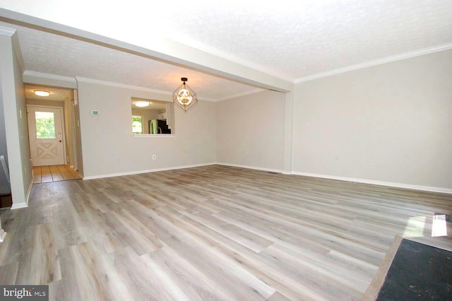 unfurnished living room with baseboards, a textured ceiling, crown molding, and wood finished floors