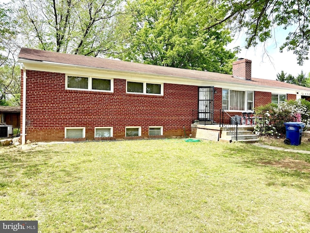 ranch-style home with a front lawn, brick siding, a chimney, and central air condition unit