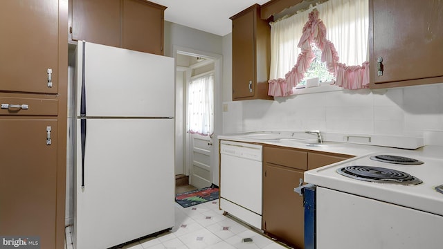 kitchen featuring light floors, white appliances, light countertops, and a sink