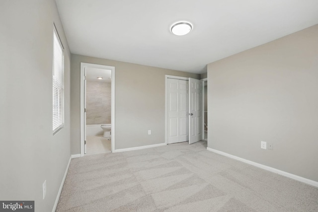 unfurnished bedroom with baseboards, ensuite bathroom, multiple windows, and carpet floors