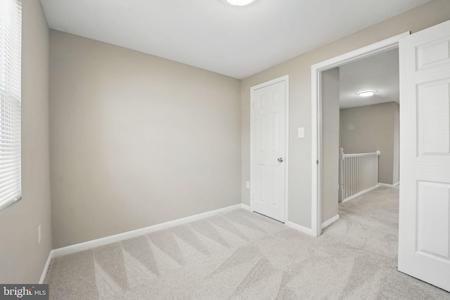 unfurnished bedroom featuring baseboards and light carpet