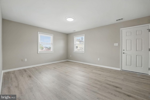 unfurnished room with visible vents, light wood finished floors, and baseboards