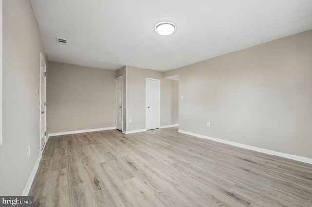 empty room featuring baseboards, light wood-type flooring, and visible vents