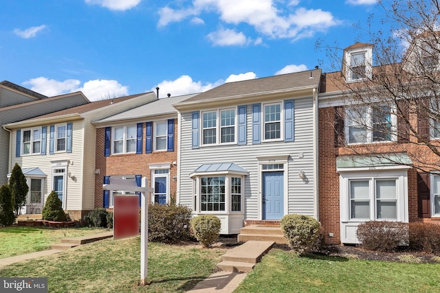 view of property featuring brick siding and a front lawn