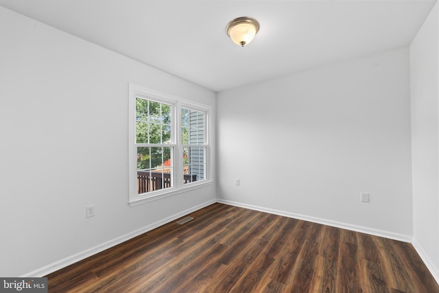 empty room with baseboards, dark wood-style flooring, and visible vents