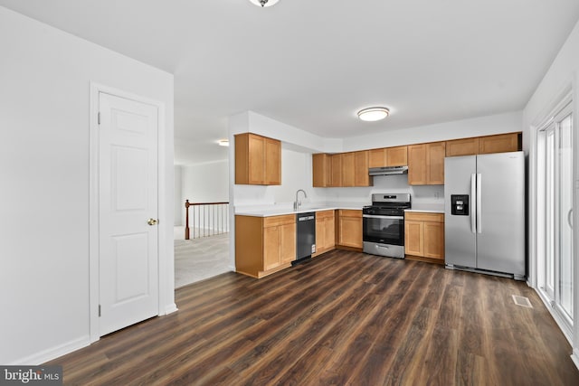 kitchen featuring light countertops, stainless steel appliances, dark wood finished floors, and under cabinet range hood