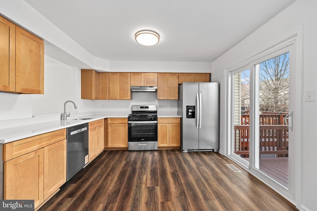 kitchen featuring appliances with stainless steel finishes, a sink, light countertops, dark wood-style floors, and under cabinet range hood
