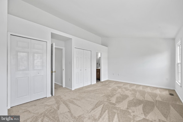 unfurnished bedroom featuring visible vents, carpet flooring, baseboards, and two closets