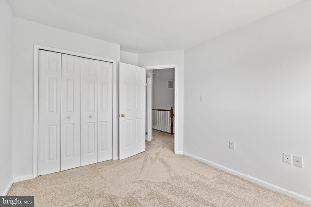 unfurnished bedroom featuring carpet floors, baseboards, and a closet