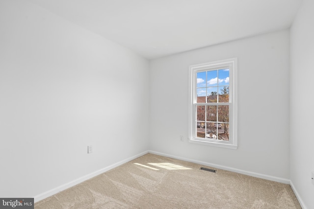 carpeted spare room featuring visible vents and baseboards