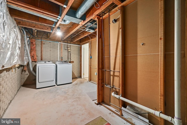 unfinished below grade area with brick wall and washing machine and clothes dryer