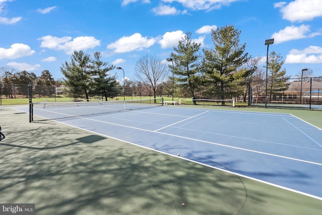 view of tennis court featuring fence and community basketball court