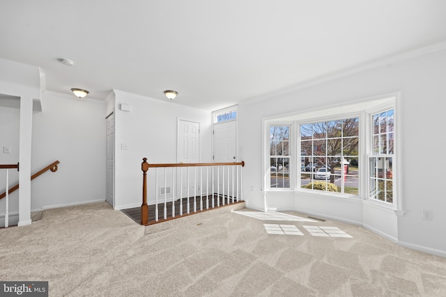 empty room with baseboards, ornamental molding, carpet, and visible vents