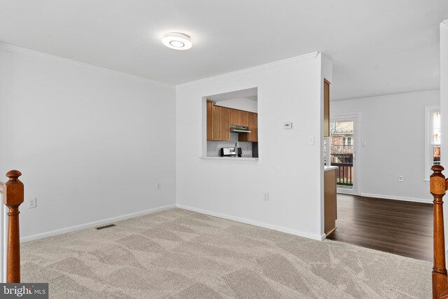 empty room with baseboards, ornamental molding, carpet, and visible vents