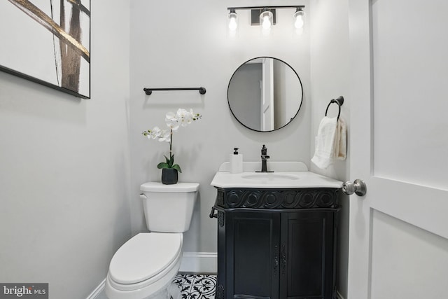half bath featuring baseboards, tile patterned flooring, toilet, and vanity