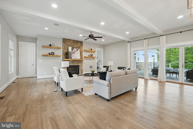 living room with beam ceiling, a fireplace, baseboards, ceiling fan, and light wood-style flooring