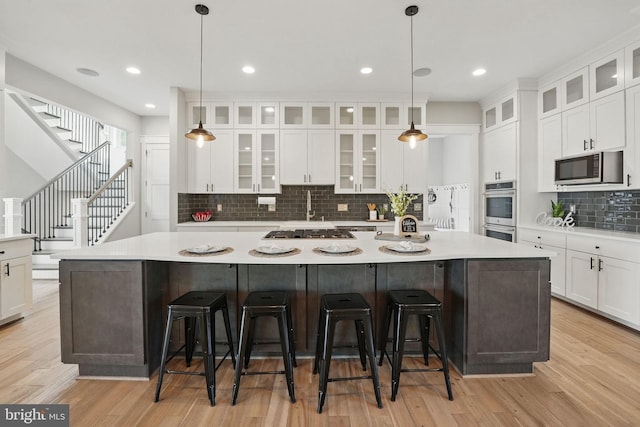 kitchen with light countertops, appliances with stainless steel finishes, decorative backsplash, and a large island