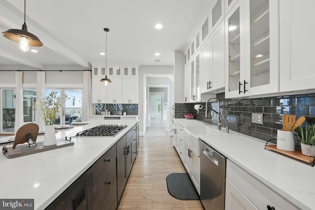 kitchen featuring white cabinets, appliances with stainless steel finishes, decorative backsplash, light wood-type flooring, and pendant lighting