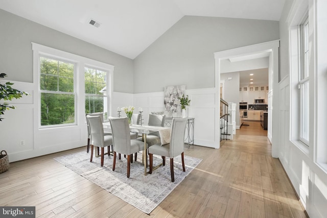 dining space with lofted ceiling and light wood-style floors