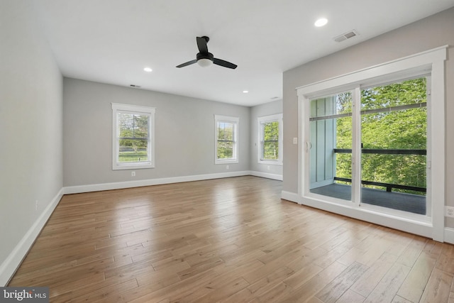 empty room with baseboards, a ceiling fan, wood finished floors, and visible vents