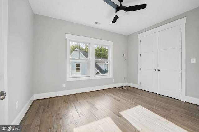 unfurnished bedroom with baseboards, visible vents, wood finished floors, and a closet