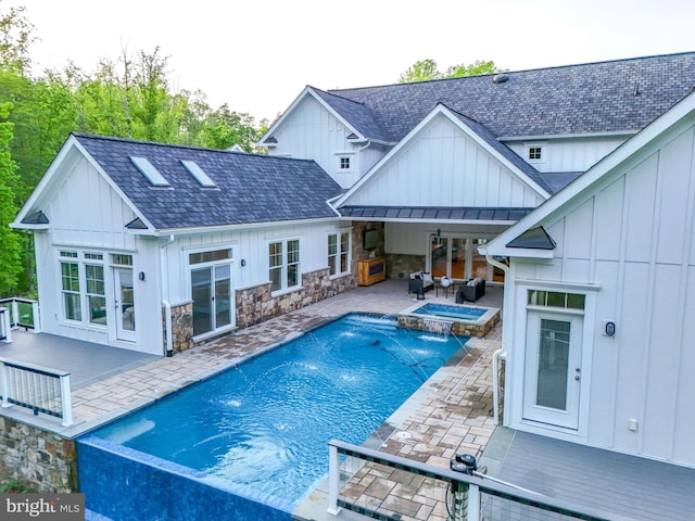 view of swimming pool with french doors, a pool with connected hot tub, a wooden deck, and a patio area