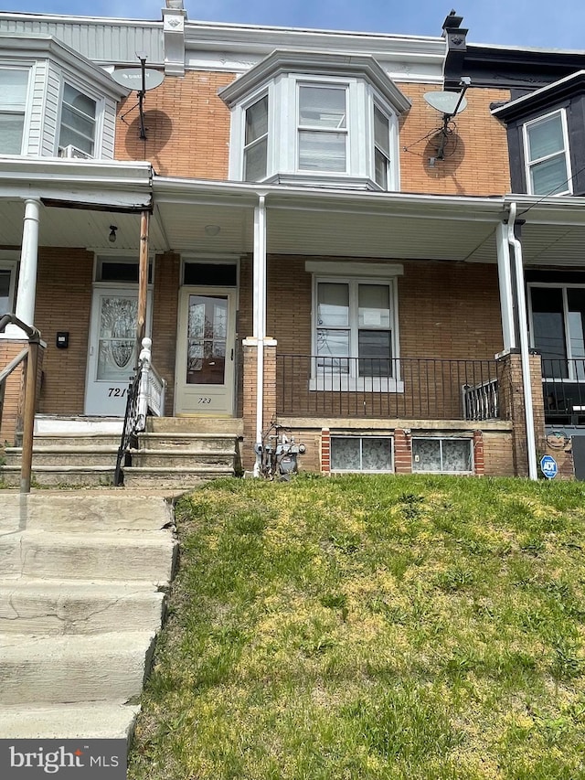 entrance to property featuring a lawn, a porch, and brick siding