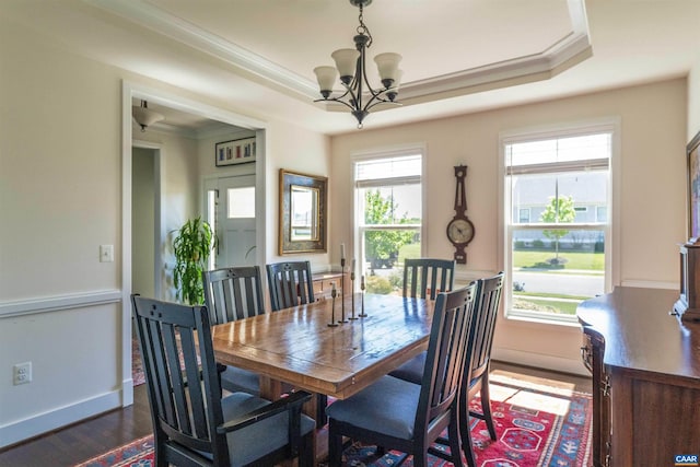dining area featuring ornamental molding, baseboards, dark wood-type flooring, a tray ceiling, and a notable chandelier