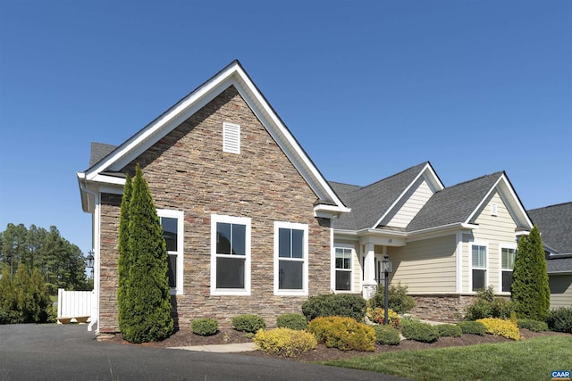 craftsman-style home featuring fence and stone siding