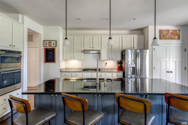 kitchen featuring hanging light fixtures, stainless steel appliances, backsplash, under cabinet range hood, and visible vents