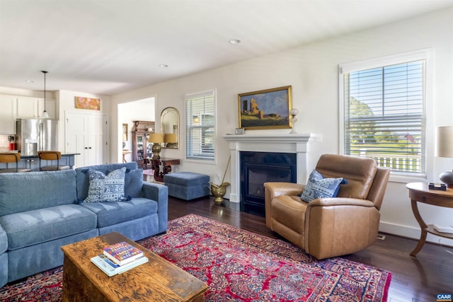 living room featuring a glass covered fireplace, baseboards, recessed lighting, and wood finished floors