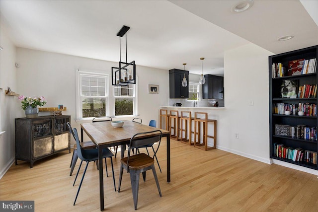 dining space with a chandelier, a healthy amount of sunlight, and light wood-style flooring