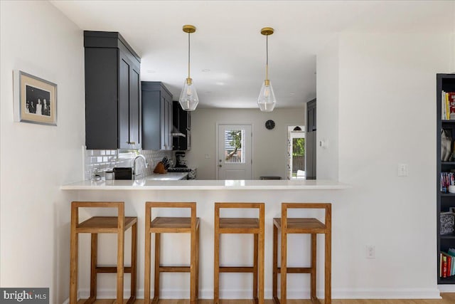 kitchen featuring backsplash, pendant lighting, a kitchen bar, and light countertops