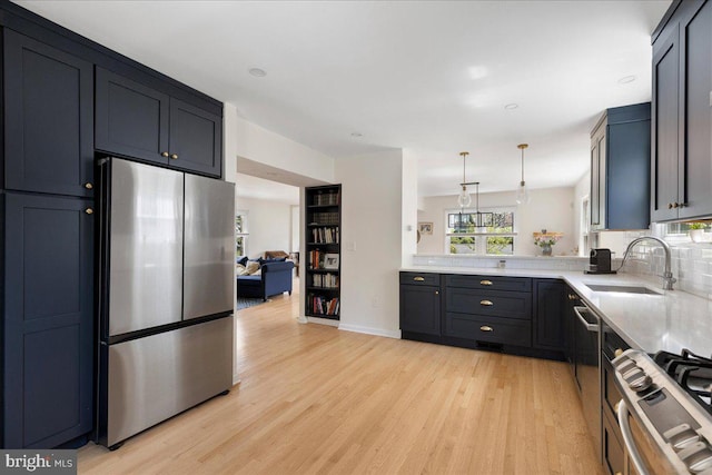 kitchen featuring pendant lighting, light wood-type flooring, a sink, light countertops, and stainless steel appliances