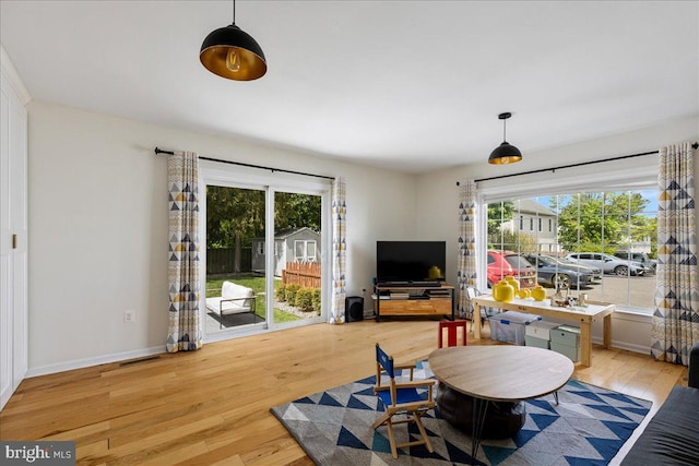living area featuring visible vents, light wood finished floors, baseboards, and a wealth of natural light