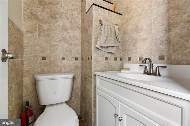 half bath featuring tile walls, vanity, and toilet
