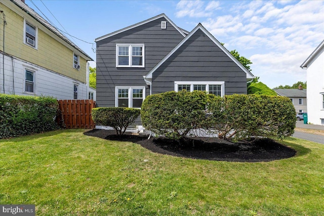 back of property featuring fence and a lawn