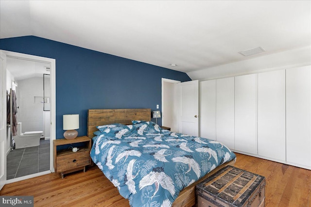 bedroom featuring visible vents, wood finished floors, and lofted ceiling