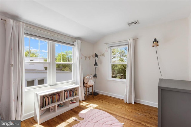 living area featuring visible vents, baseboards, lofted ceiling, and wood finished floors