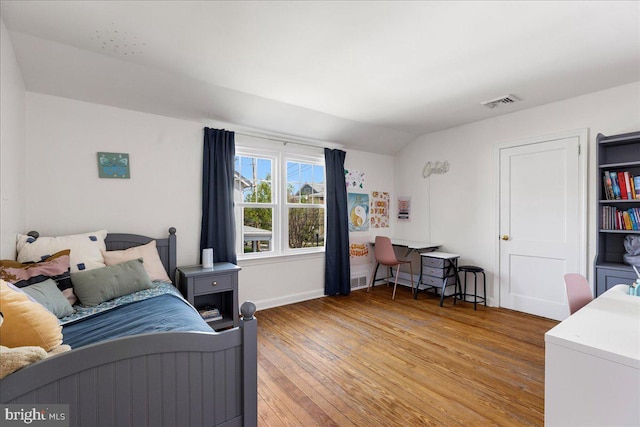 bedroom with light wood-style floors, baseboards, visible vents, and vaulted ceiling