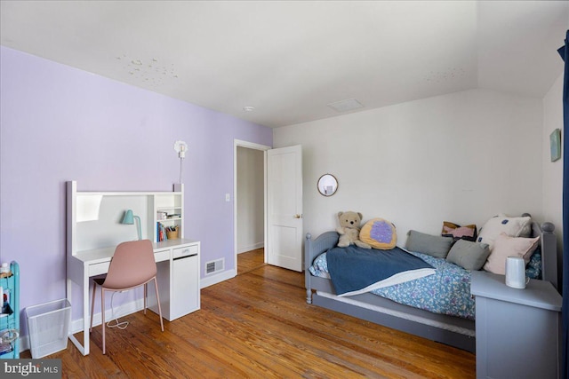 bedroom with baseboards, visible vents, wood finished floors, and lofted ceiling