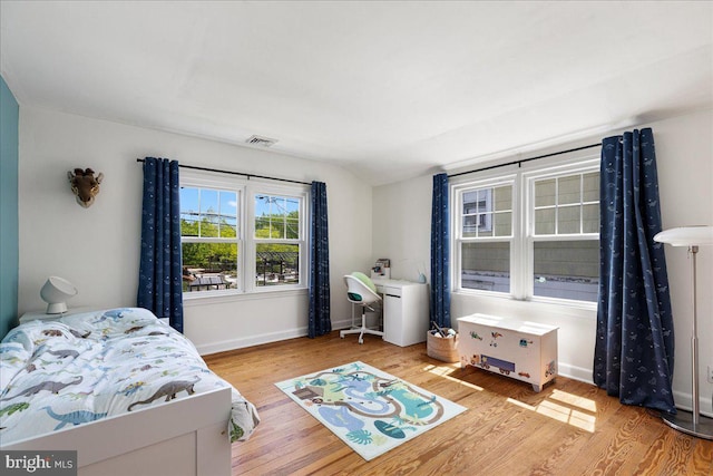 bedroom featuring baseboards, vaulted ceiling, wood finished floors, and visible vents