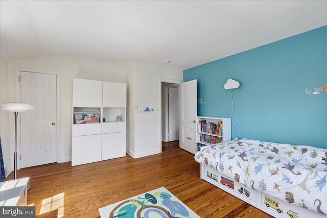 bedroom with vaulted ceiling and wood finished floors