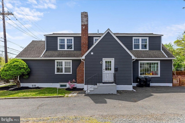 exterior space featuring roof with shingles, fence, and a chimney