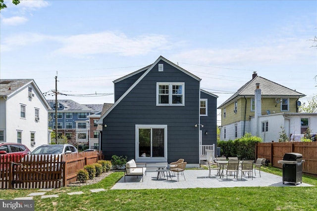 back of property with a lawn, fence private yard, and a patio area
