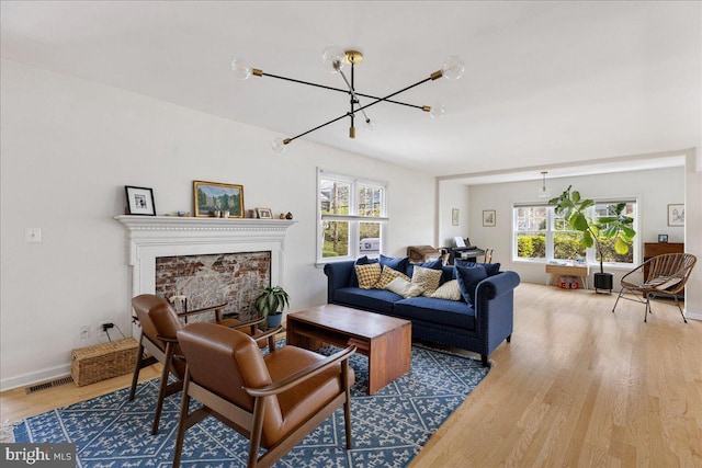 living area with visible vents, wood finished floors, a notable chandelier, and a healthy amount of sunlight