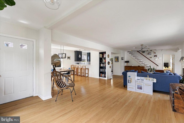 foyer featuring baseboards, light wood finished floors, a fireplace, and stairway