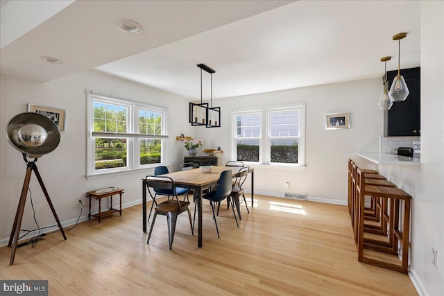 dining space featuring baseboards, visible vents, and light wood-style flooring